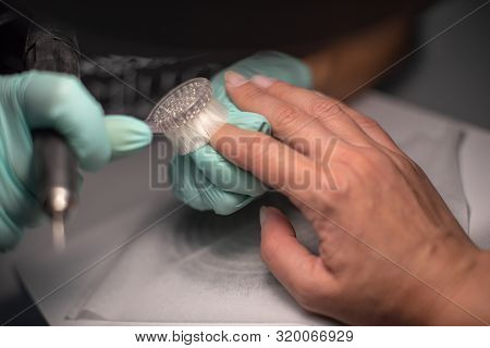 A Manicure Hand With A Nail Lies On A Manicure Hand In Blue Hygienic Gloves.hands On The Manicure Of