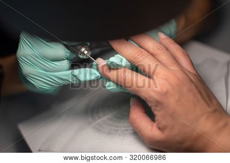 A Manicure Hand With A Nail Lies On A Manicure Hand In Blue Hygienic Gloves.hands On The Manicure Of