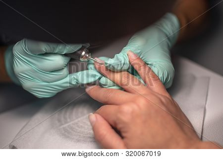 A Manicure Hand With A Nail Lies On A Manicure Hand In Blue Hygienic Gloves.hands On The Manicure Of