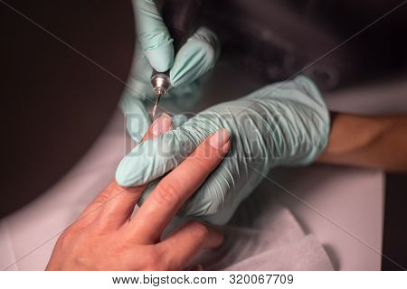 A Manicure Hand With A Nail Lies On A Manicure Hand In Blue Hygienic Gloves.hands On The Manicure Of
