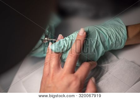 A Manicure Hand With A Nail Lies On A Manicure Hand In Blue Hygienic Gloves.hands On The Manicure Of