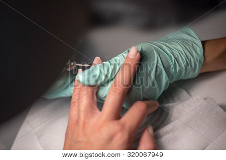 A Manicure Hand With A Nail Lies On A Manicure Hand In Blue Hygienic Gloves.hands On The Manicure Of