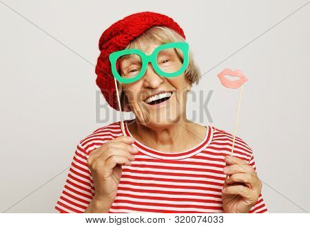 funny grandmother wearing red clothes holding falce glasses and ready for party
