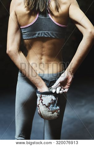 Back View Of Woman Climber Is Chalking Hands With White Chalk Powder Before Climb In Indoor Climbing