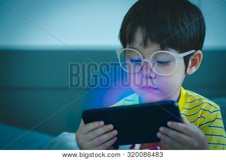Cute Little Child Watching Cartoon On Smartphone In The Dark Room. Dangers Of Blue Light Damage His 