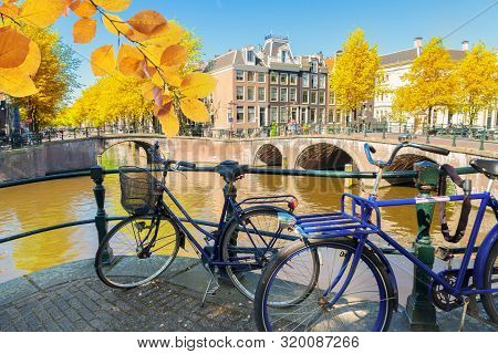 Bicycles, Houses And Bridge Of Amsterdam Over Canal Ring Landmark In Old European City At Fall, Hola