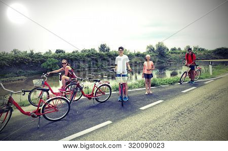 Family With Young Boys And Little Girl With Bike On The Road In Summer