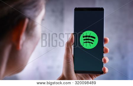 Poznan, Pol - Jul 10, 2019: Woman Holding Smartphone Displaying Logo Of Spotify, A Swedish Audio Str