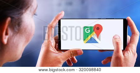 Poznan, Pol - Jul 10, 2019: Woman Holding Smartphone Displaying Logo Of Google Maps, A Web Mapping S
