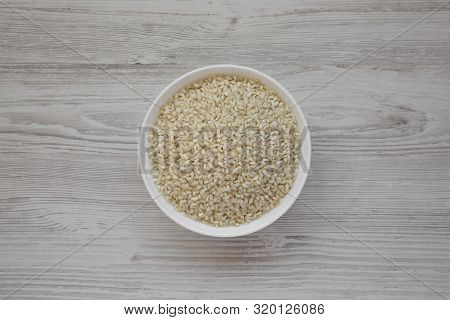 Organic Arborio Rice In A White Bowl On A White Wooden Background, Top View. Flat Lay, Overhead, Fro