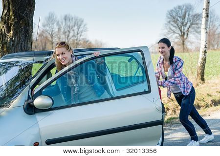 Vehicle breakdown two young women pushing car down the road