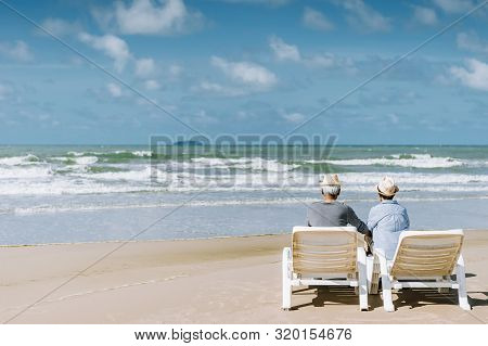 Asian Senior Couple Or Elderly People Walking And Siting At The Beach On Their Weekend Vacation Holi