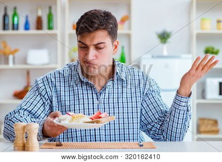 Young husband eating tasteless food at home for lunch