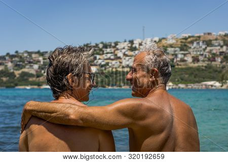 Happy Senior Couple By The Sea Enjoying Retirement. Elderly Couple Hugging. Summet Time.
