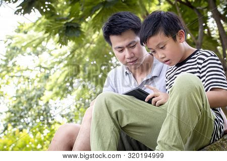 Father And Son Using A Tablet And Smiling Happy While Spending Time Together At Patk , Happy Family 