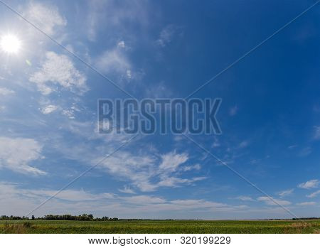 Fragment Of The Sky With Cirrus And Cumulus Clouds And Sun Over Field