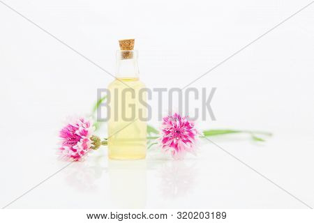 Essence Of Lavender Flowers On White Background In Beautiful Glass Bottle