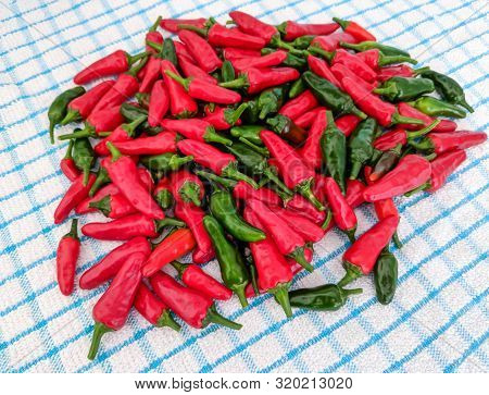 Red And Green Chilli Peppers. Large Fresh Pile On A Kitchen Tea Towel Background.