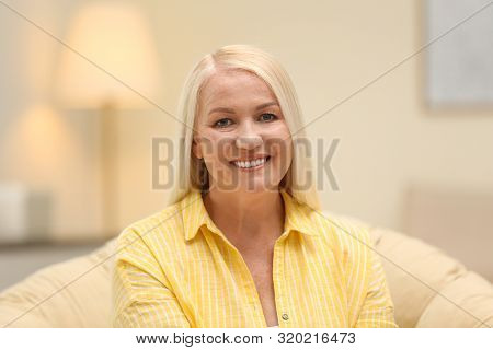 Portrait Of Happy Mature Woman Sitting In Papasan Chair At Home