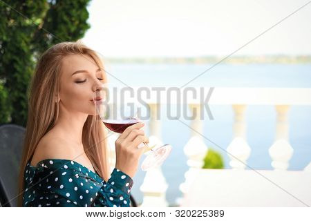 Beautiful Woman Drinking Glass Of Wine On Restaurant Terrace