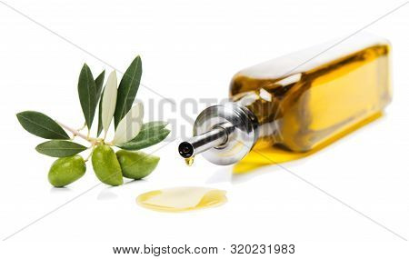 Olive Oil Dripping From A Glass Bottle And A Twig Of Olive Tree With Green Olives Isolated On White 