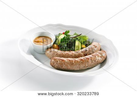 Macro shot of Munich sausages for frying made from pork and beef with mustard sauce and mixed salad isolated. Traditional German rostbratwurst, wurst or bratwurst with vegetables and greens closeup