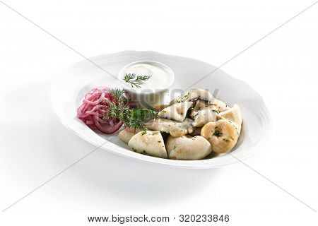 Pickles set with homemade pickled milk mushrooms, marinated red onion rings and sour cream on white restaurant plate isolated. Salted Lactarius resimus mushroom with oil and fresh chopped dill