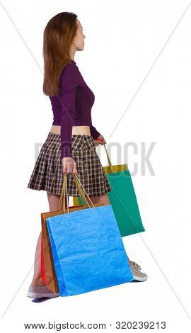 back view of woman in striped T-shirt with shopping bags . beautiful brunette girl in motion.   Isolated over white background. A blonde woman is walking sideways with bags.