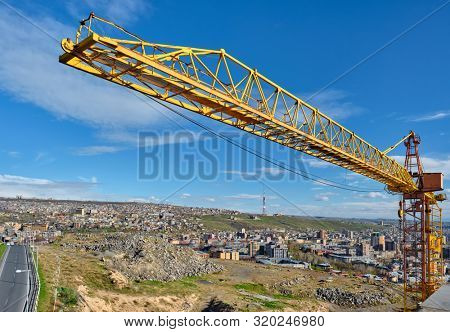 Yellow construction jib crane tower against blue sky