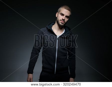 male model wearing hoodie and posing in stuio on grey background