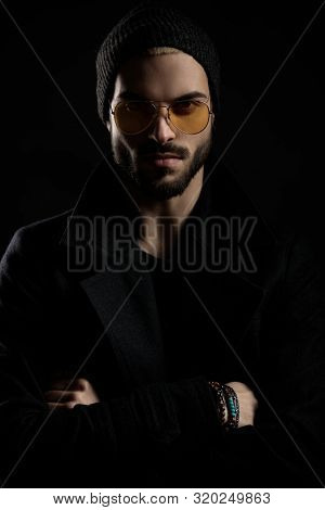 man with beard standing with hands crossed wearing sunglasses and bracelets