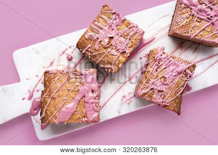 Pink Brownies With Ruby Chocolate On White Marble Cutting Board And Pink Background. Close-up Image 