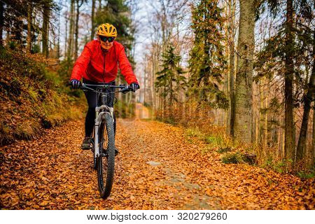 Cycling woman riding on bike in autumn mountains forest landscape. Woman cycling MTB flow trail track. Outdoor sport activity.