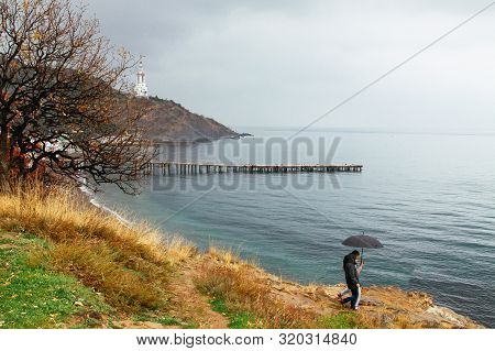 Couple With Umbrella Walking In Rain. Couple Travel In Rainy Weather Near Sea. Malorechenskoye, Crim