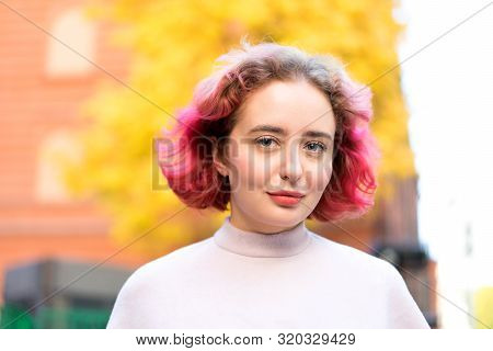 Beautiful Woman With Red Dyed Hair And Background Of Autumn Yellow Leaves.
