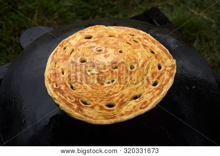 Pita Bread Baking On A Saj Or Tava On Fire, Close-up. Traditional Arabic Pita Bread