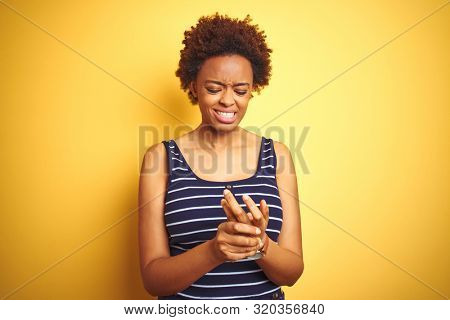 Beauitul african american woman wearing summer t-shirt over isolated yellow background Suffering pain on hands and fingers, arthritis inflammation