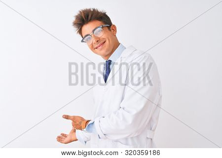 Young handsome sciencist man wearing glasses and coat over isolated white background Inviting to enter smiling natural with open hand