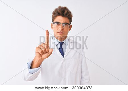 Young handsome sciencist man wearing glasses and coat over isolated white background Pointing with finger up and angry expression, showing no gesture