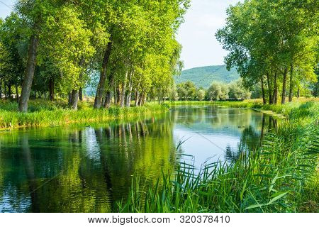 Beautiful Gacka River Flowing Between Trees And Fields, Summer View, Lika Region Of Croatia
