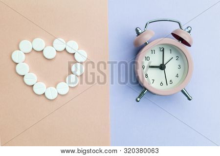 Pills Lie Next To The Alarm Clock On A Light Background. Healthcare And Medicine Concept.
