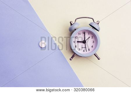 Pills Lie Next To The Alarm Clock On A Light Background. Healthcare And Medicine Concept.