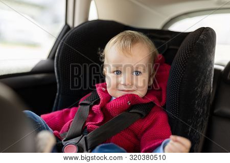 Cute Caucasian Toodler Boy Sitting In Child Safety Seat In Car During Road Trip. Adorable Baby Smili