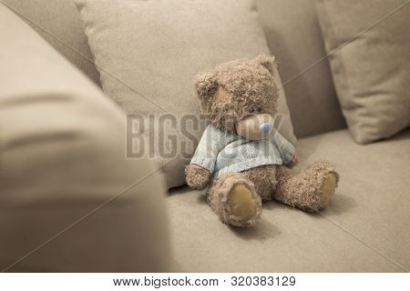 Lonely Teddy Bear Is On The Brown Sofa. Lonely Doll