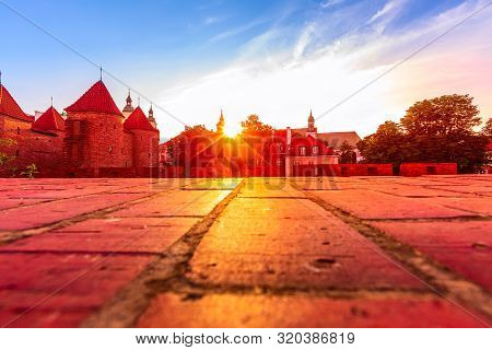 Warsaw, Poland Sunset View Of Barbican Or Barbakan Wall And Old Town Houses