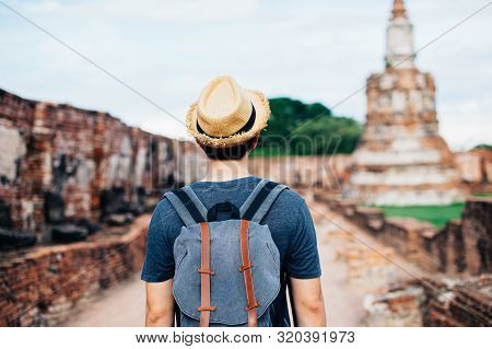 Back Of Asian Male Solo Traveller With Travel Hat Walks Inside Historical Buddhist Ruins Heritage Wi