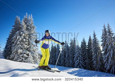 Young Happy Smiling Woman Posing On Skis In Goggles Looking On Camera Before Skiing From High Snowy 