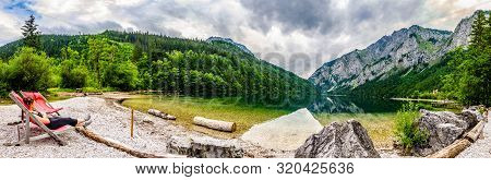 Landscape Panorama With Woman On Sunbed Next To The Lake Leopoldsteinersee, Styria, Austria. Travel 
