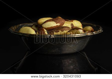 Lot Of Whole Raw Brown Brazil Nut In Metal Bowl Isolated On Black Glass