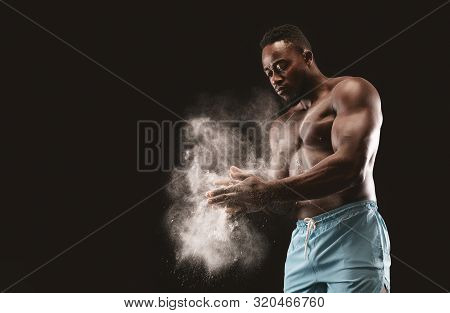 Young Bare-chested African Sportsman Applying Talcum Powder On His Hands, Black Studio Background, F